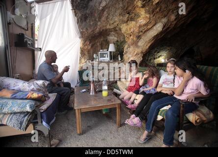 Silwan, Jerusalem, Palästina. 26. August 2013. Khaled al-Zeer al-Husaini, 39, schaut TV mit seinen Kindern in seiner Höhle im Osten Jerusalems arabische Viertel Silwan, 26. August 2013. Al-Husaini ist Vater von fünf Kinder Leben in einer Höhle, das war ein Stall für die Tiere, nach israelische Behörden seinen eigenen vier Wänden unter dem Vorwand der Gebäude ohne Genehmigung Kredit vor 3 Tagen abgerissen: Saeed Qaq/APA Images/ZUMAPRESS.com/Alamy Live News Stockfoto