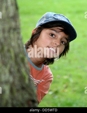 Porträt von Brünette Junge spähen hinter Baum Stockfoto