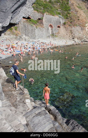 RIOMAGGIORE, 6. August 2013: Menschen genießen den steinigen Strand in der Nähe von Riomaggiore Teil von Italien Cinqueterre am august 6 2013 benannt. Stockfoto