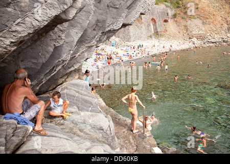 RIOMAGGIORE, 6. August 2013: Menschen genießen den steinigen Strand in der Nähe von Riomaggiore Teil von Italien Cinqueterre am august 6 2013 benannt. Stockfoto