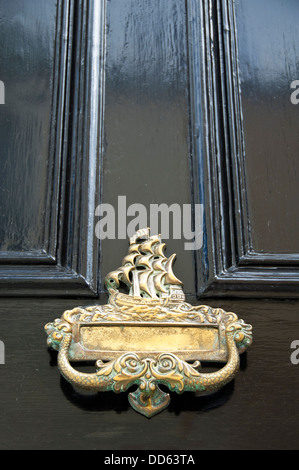 Vertikale Nahaufnahme eines großen nautischen Themen Messing Klopfer und Briefkasten auf einem schwarzen Tor. Stockfoto