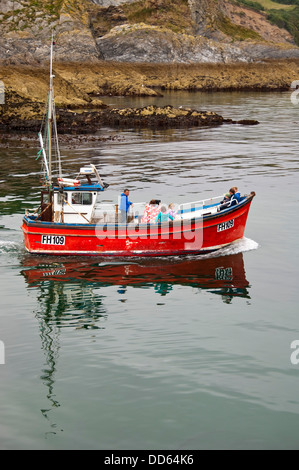 Vertikale Nahaufnahme des Touristen auf eine kleine rote Fischkutter in Cornwall. Stockfoto