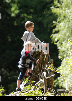 Zwei junge Burschen Klettern auf die Wurzeln der einen umgestürzten Baum im Wald, UK 2013 Stockfoto