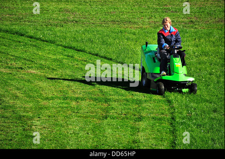 Eine Frau, die ein Feld mit einer Fahrt auf Mäher Gras schneiden Stockfoto