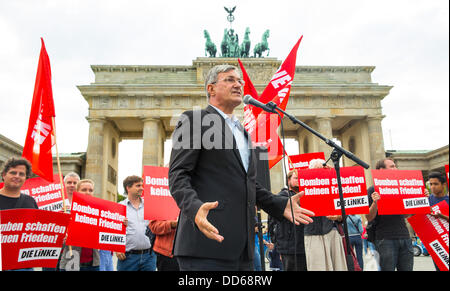 Berlin, Deutschland. 27. August 2013. Der Vorsitzende der Partei Die linke (die linke), Bernd Riexinger, spricht während einer Demonstration vor dem Brandenburger Tor in Berlin, Deutschland, 27. August 2013. Die Linkspartei ist gegen ein militärisches Eingreifen in Syrien. Plakate im Hintergrund lesen "Bomben nicht Frieden bringen!". Foto: HANNIBAL/Dpa/Alamy Live News Stockfoto