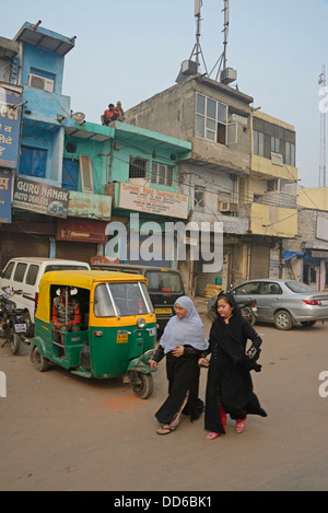 Zwei muslimische Mädchen gehen an einem tut-tut in einem Slum-Viertel von Alt-Delhi in Indien vorbei Stockfoto