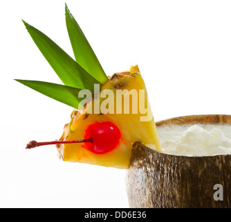Nahaufnahme von einer tropischen Kokosnuss-Drink, garniert mit einer Ananasscheibe mit Blättern und einer Kirsche Stockfoto