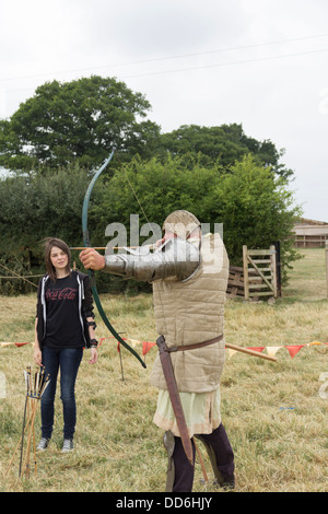 Teenager-Mädchen eine Demonstration wie man einen Langbogen Feuer mittelalterlichen Reenactor auf eine "Have-a-Go" Bogenschießen-Ausstellung erteilt. Stockfoto