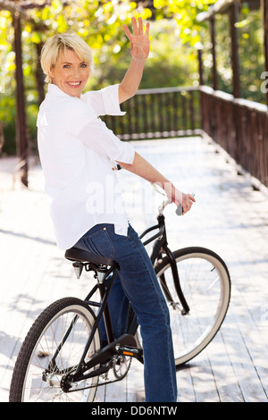 fröhliche mittlere gealterte Frau in einem Motorrad winken verabschieden Stockfoto