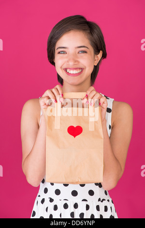 Junge lächelnde Frau hält einen Valentine Tag Shopping Tasche Stockfoto