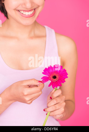 Romantische Porträt jungen multirassische Frau Kommissionierung Blütenblätter von einer rosa Gerbera daisy Stockfoto