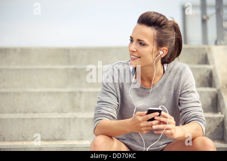 Glücklich attraktive Sportler sitzen und anhören von MP3-Musik beim Ausruhen Stockfoto