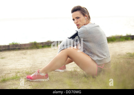 Europäerin ausruhen und sitzen auf dem Rasen nach dem Ausführen von Training / Bewegung. Stockfoto