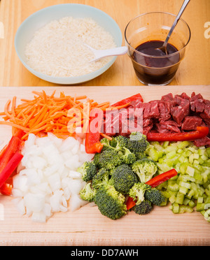 Rind braten Zutaten auf Schneidebrett mit Reis und Soja-Sauce im Hintergrund Stockfoto