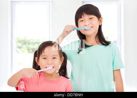 zwei glückliche kleine Mädchen, die ihre Zähne putzen Stockfoto