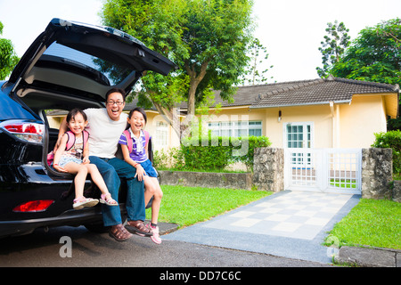 glückliche Familie sitzt im Auto und ihr Haus hinter Stockfoto