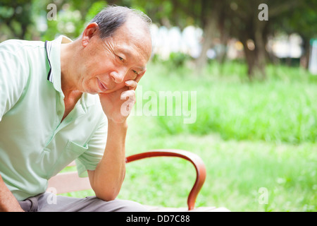 deprimiert senior Mann sitzt im park Stockfoto