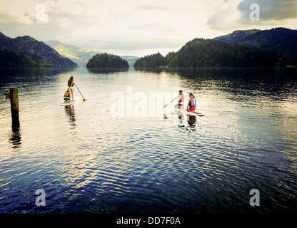 Mädchen-Paddle-boarding auf See Stockfoto