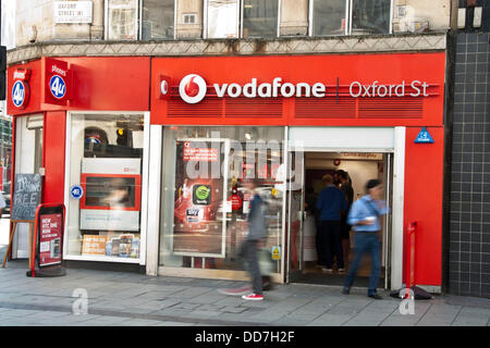 London, UK. 28. August 2013. Der Vodafone-Shop in der Oxford Street mit längere Belichtungszeit unscharf Fußgänger. Am 29. August startet Vodafone 4G Service für Kunden in London. Das Unternehmen investierte £ 900 Millionen im Netz. Vodafone will roll-out der Service für 12 weitere Städte einschließlich Sheffield, Leeds und Manchester vor Ende 2013. Kunden auf einer SIM-Karte nur 12-Monats-Vertrag werden voraussichtlich £26 pro Monat, £5 mehr als die durchschnittliche 3G-Dienst zu zahlen. Bildnachweis: Pete Maclaine/Alamy Live-Nachrichten Stockfoto