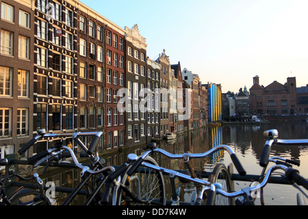 Berühmten niederländischen Gebäude in der Dämmerung mit Fahrrädern geparkt entlang der Seite der Kanal in Amsterdam. Stockfoto