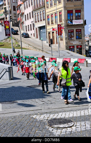 Portugiesische Schulkinder auf einem Ausflug mit ihren Lehrern, mit farbigen Kappen außerhalb der Bahn Bahnhof, Porto, Porto, Portugal Stockfoto