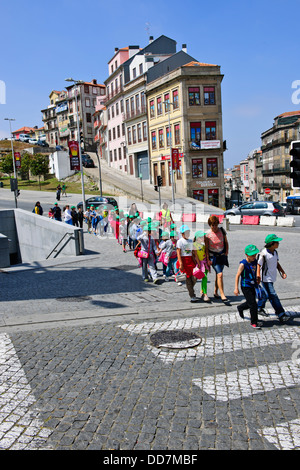 Portugiesische Schulkinder auf einem Ausflug mit ihren Lehrern, mit farbigen Kappen außerhalb der Bahn Bahnhof, Porto, Porto, Portugal Stockfoto