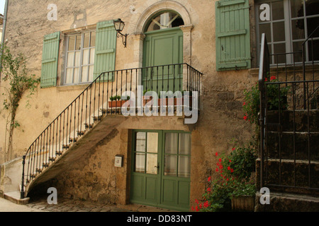 Altes französisches Landhaus mit Treppe zum ersten Stock. Tür und Fenster haben grüne hölzerne Fensterläden gemalt Stockfoto