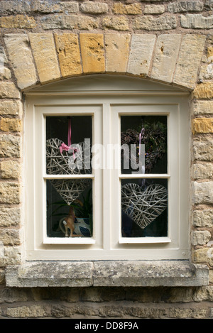 Handwerk-Herzen in einem Cotswold-Landhaus-Fenster. England Stockfoto