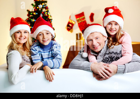 Vierköpfige Familie tragen Weihnachtsmann-Mützen werden bereit für Weihnachten Stockfoto