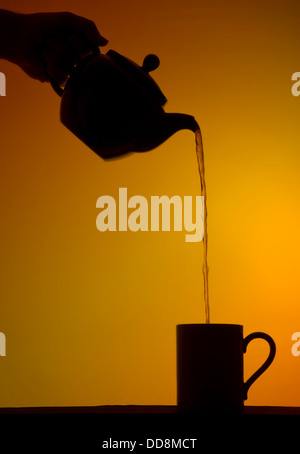 Silhouette der Tee in einen Becher aus einem Topf gegossen Stockfoto