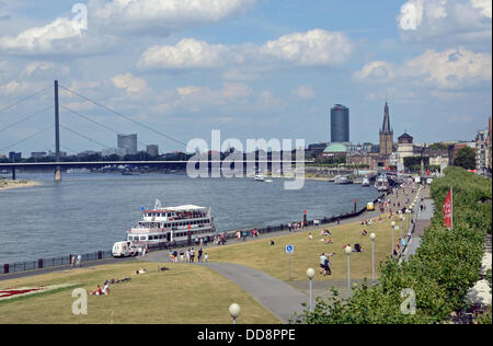 Rhein promenade in Düsseldorf, Nordrhein-Westfalen, mit Oberkassel Rhine Brücke (l-R), Sky Office Tower, ERGO Büroturm, Lambertuskirche und seinen (Schlossturm) im Hintergrund. In der Front ist ein Passagierschiff der Köln-Düsseldorfer Rheinschifffahrt ersichtlich. Bild vom 3. August 2013. Stockfoto