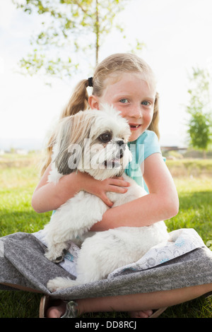 Kaukasische Mädchen umarmt Hund Gras Stockfoto