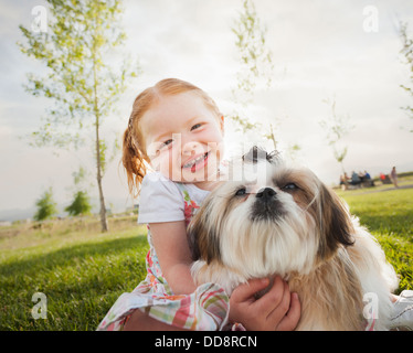 Kaukasische Mädchen umarmt Hund Gras Stockfoto