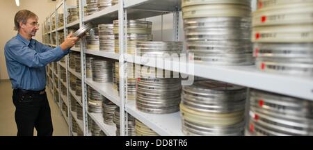 Der Direktor der Abteilung für Filmrestaurierung und Konservierung, Egbert Koppe, sitzt vor Regale gefüllt mit Filmrollen und Filmmaterial in silbernen Dosen in einem Lagerraum bei German Federal Film Archive in Hoppegarten, Deutschland, 12. August 2013 gespeichert. Koppe ist besorgt über den desolaten Zustand von einigen Film-Depots, die auf verschiedene Einrichtungen an verschiedenen Orten verteilt sind. Gespräche gehen seit Jahren in Bezug auf eine neue zentrale Einrichtung für Film Konservierung und Archivierung in Hoppegarten bei Berlin. Foto: Patrick Pleul Stockfoto