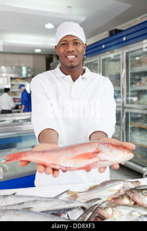 Gemischte Rassen Lebensmittelhändler Zubereitung von Fisch im Markt Stockfoto