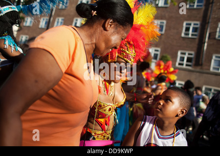 Zwei Frauen in sprechen, ein kleiner Junge während sie entlang in die Parade tanzen. Stockfoto