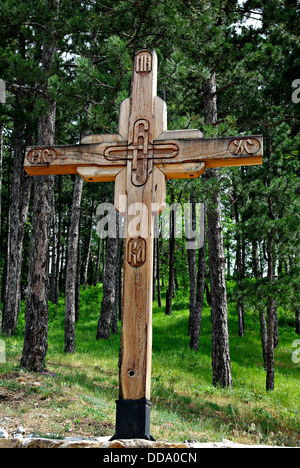 Holzkreuz in einem Kiefernwald an einem sonnigen Sommertag. Stockfoto
