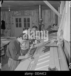 Dieses Foto zeigt eine Szene aus dem Schilderladen im Rohwer Relocation Center in McGehee, Arkansas. Das Zentrum war eines der Internierungslager während des Zweiten Weltkriegs, in dem japanische Amerikaner umgesiedelt wurden. Die Schilderei war Teil des täglichen Betriebs des Lagers. Stockfoto