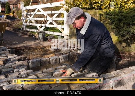 selbst bauen, Haus, harte Landschaftsbau, Handwerker, Verlegung zurückgefordert Granit Pflastersteine am Eingang Einfahrt Stockfoto