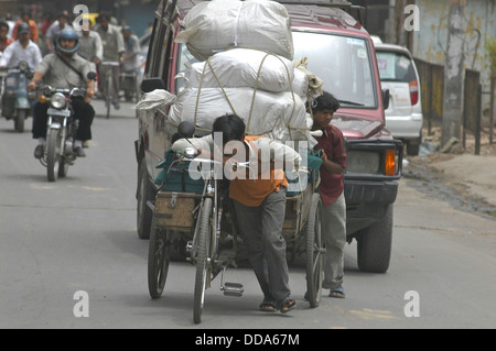 Ein Mann zieht eine schwere Last auf einer belebten Straße Szene. Stockfoto