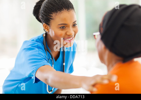Pflege der afrikanischen Krankenschwester tröstet senior Patienten im Büro Stockfoto