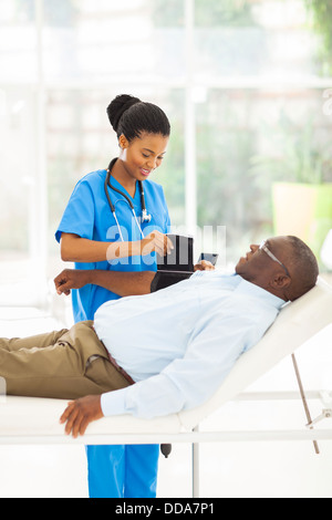 ziemlich afrikanischen Krankenschwester ältere Patienten Blutdruck messen Stockfoto