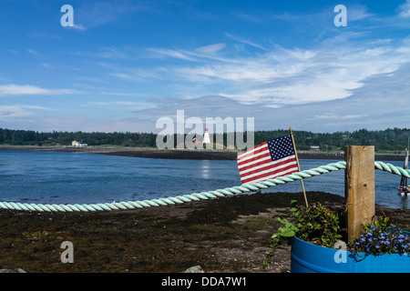 Eine amerikanische Flagge in einen Blumentopf und ein blauer Lichtschlauch im Vordergrund & Leuchtturm entfernt an der Küste in Lubec Maine. Stockfoto