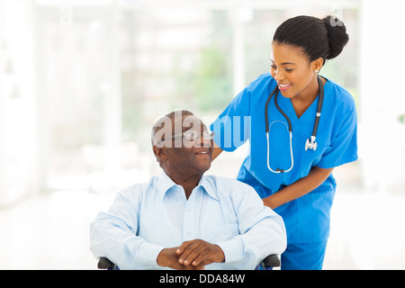 schöne afrikanische Krankenschwester kümmert sich um ältere Patienten im Rollstuhl Stockfoto