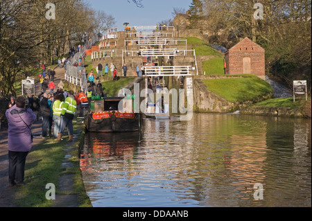 Menschen auf der belebten sonnigen Canal Leinpfad durch Boote, Wandern & Suchen bei Renovierungsarbeiten - Tag der offenen Tür, Bingley's fünf Aufstieg Schlösser, West Yorkshire, England, UK. Stockfoto