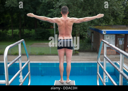 Mann auf Sprungbrett im öffentlichen Schwimmbad bereit zum Sprung Stockfoto
