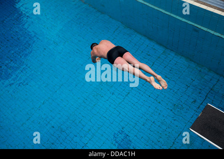 Mann springt vom Sprungbrett im Schwimmbad Stockfoto