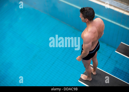 Mann auf Sprungbrett im Schwimmbad über dem Wasser Stockfoto