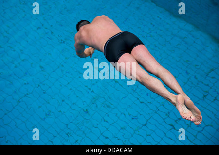 Mann springt vom Sprungbrett im Schwimmbad Stockfoto