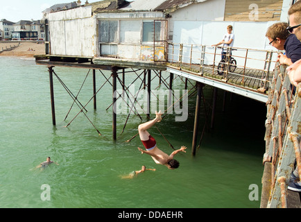 Ein Teenager taucht oder Grabsteine, aus dem Pier in Bognor Regis. Er hat einen "Back Flip' und gut im Wasser gelandet. Stockfoto